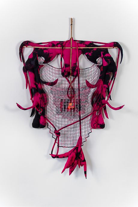 A wall soft sculpture tie dyed in black and pink with filet lace and netting elements framed in bamboo that are tied using square lashing knots. Within the filet lace is an embedded gay pornographic image using a sublimation dye technique.