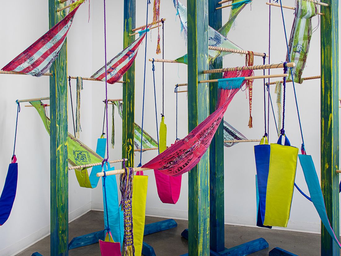 Colorful woven forms using backstrap weaving on posts installation.