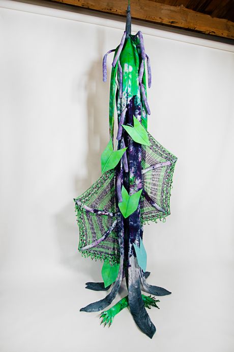 Hand-dyed primarily in electric green and purples, this tall soft sculpture resembles a spadix plant with wide knitted wings.