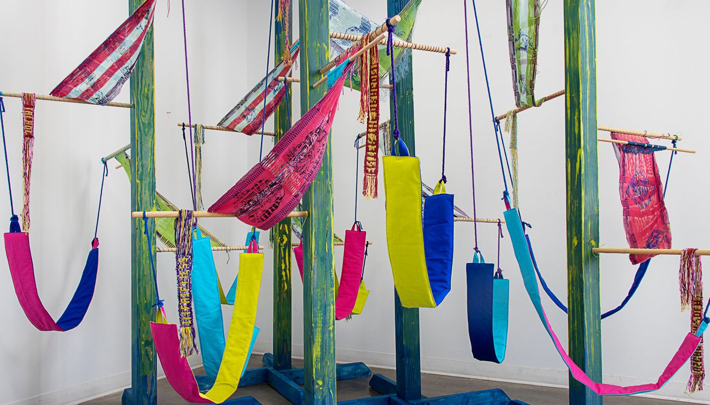 Colorful woven forms using backstrap weaving on posts installation.