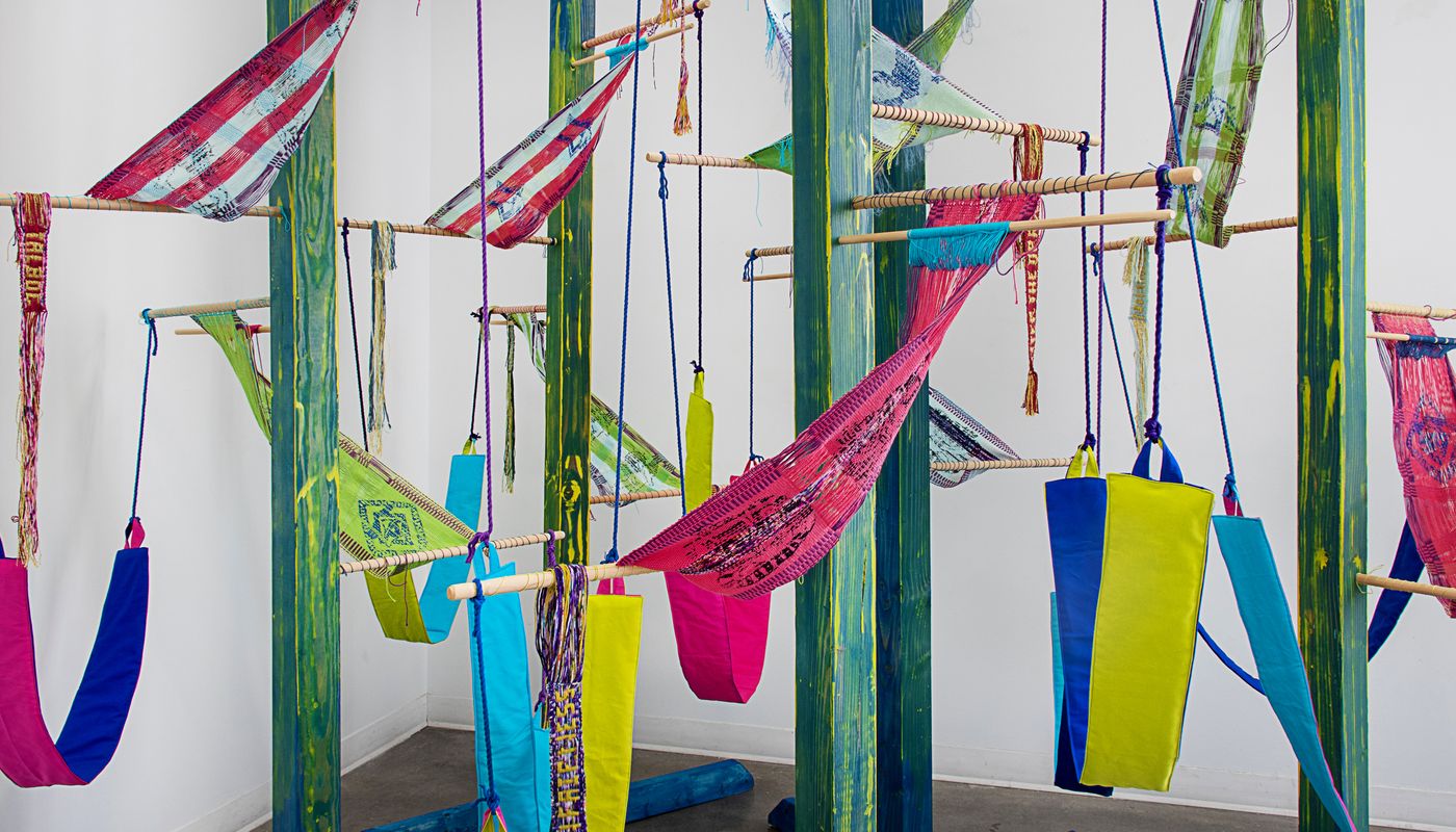 Colorful woven forms using backstrap weaving on posts installation.