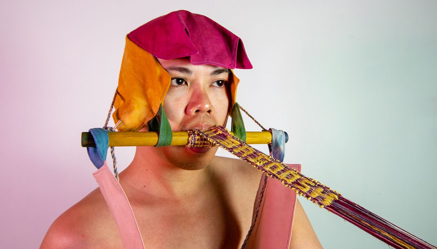 Backstrap weaving attached to a artist mouth and propped by fabric mask.
