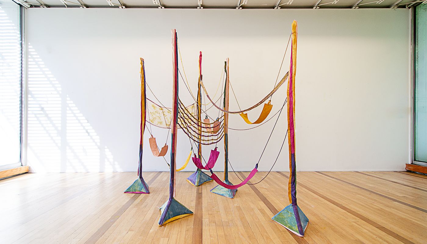 Colorful woven forms using backstrap weaving on fabric posts dyed with onion skins, indigo, avocado skins and pits, goldenrod, and sappanwood.